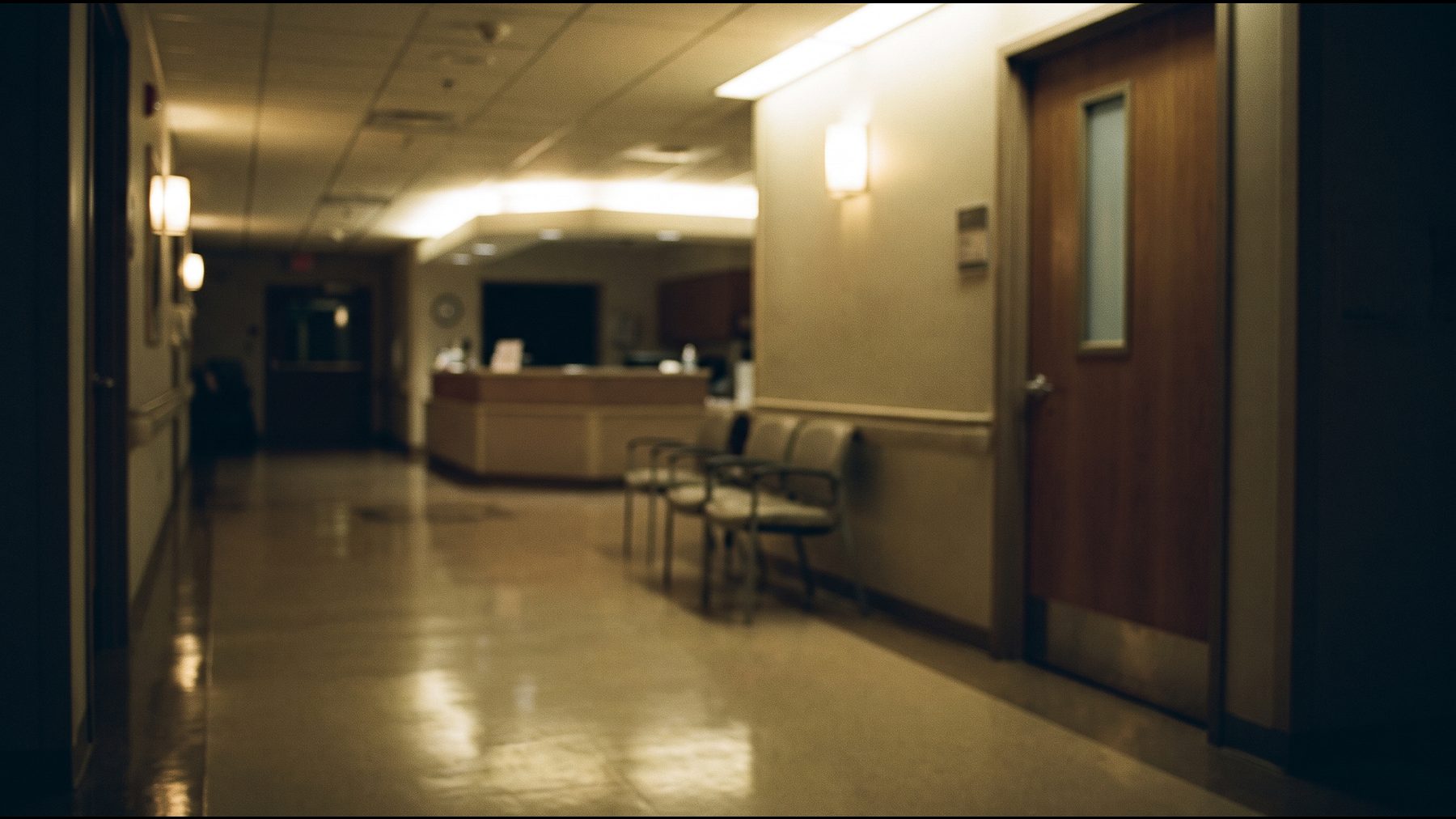 An empty hospital maternity corridor at night with soft light reflecting on a polished floor