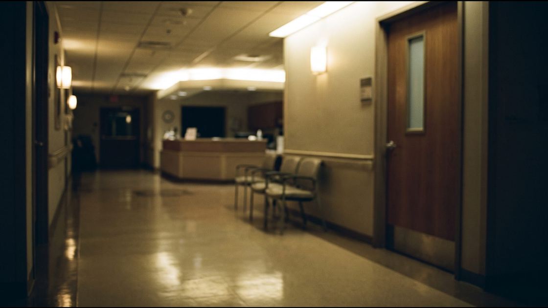 An empty hospital maternity corridor at night with soft light reflecting on a polished floor
