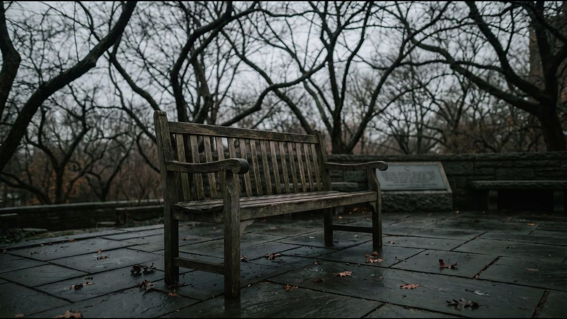 An empty wooden bench in a quiet New York memorial garden on an overcast morning